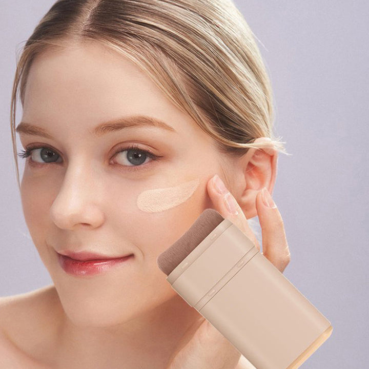 "Sminkstick med inbyggd borste, beige nyans, för enhetlig täckning och naturlig finish, kompakt och resvänlig."