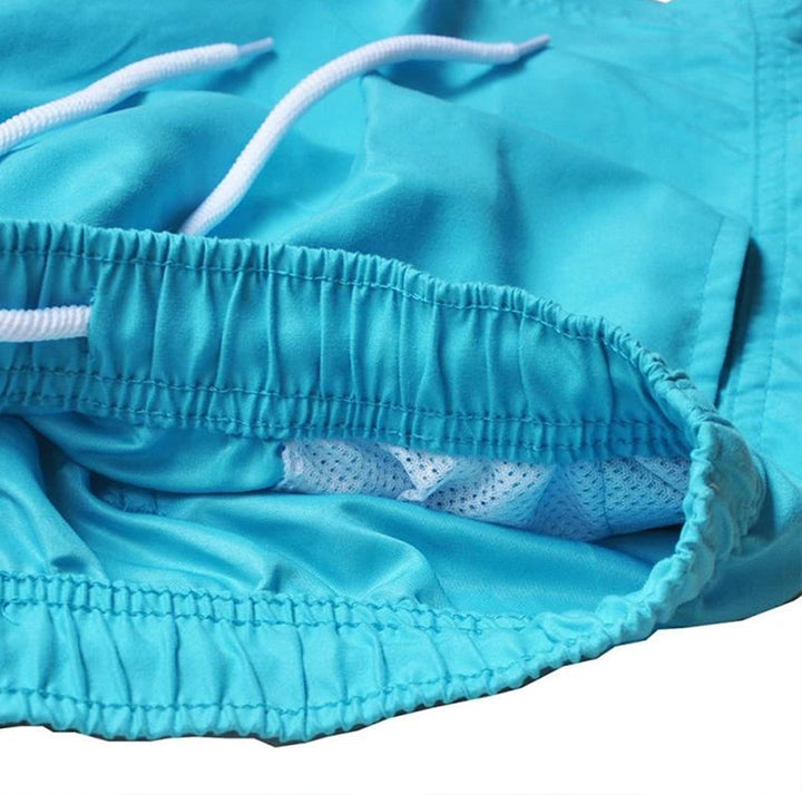 "Snabbtorkande badshorts i grått med ljusblå detaljer, elastisk midja och trendig design för män på sommaren."